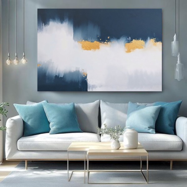 A living room with a white couch and a canvas print featuring an abstract design with blue, white, and gold strokes.